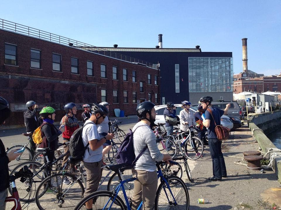 Guided bicycle tour group gathered at riverside industrial pier