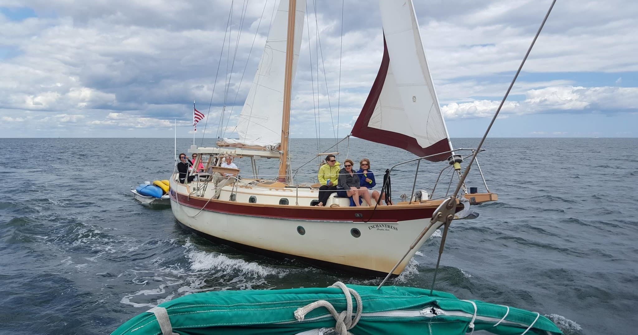 Classic sailboat under full sail on open water near horizon