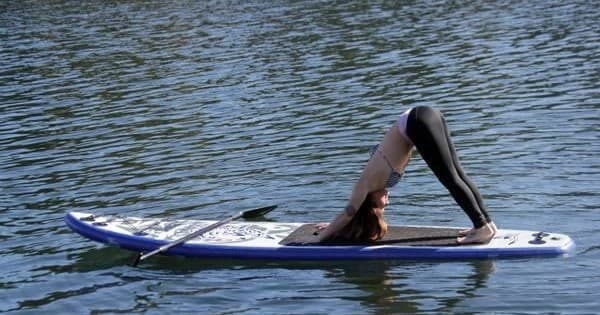 Person doing yoga pose on paddleboard in flat coastal water