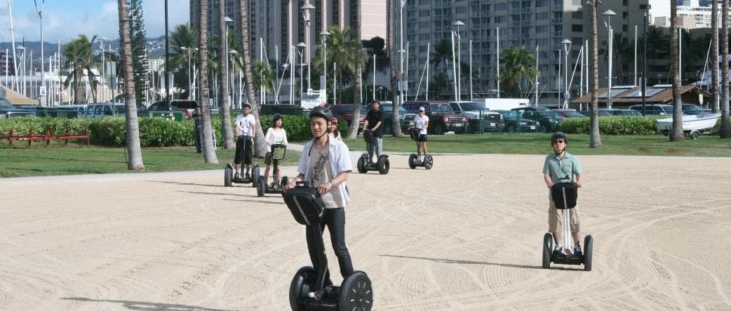 Guided Segway riders on beachfront path near Waikiki marina