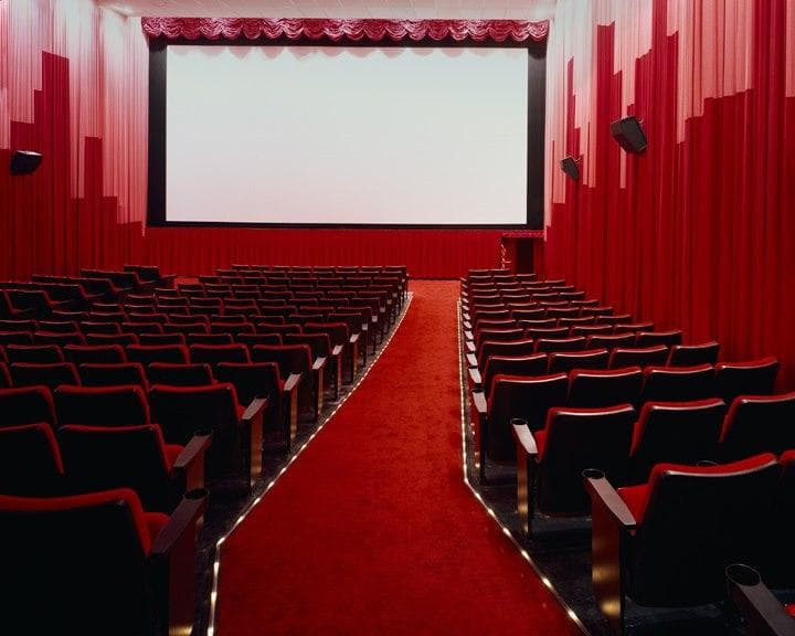 Empty red-seat movie theater interior with stage and screen