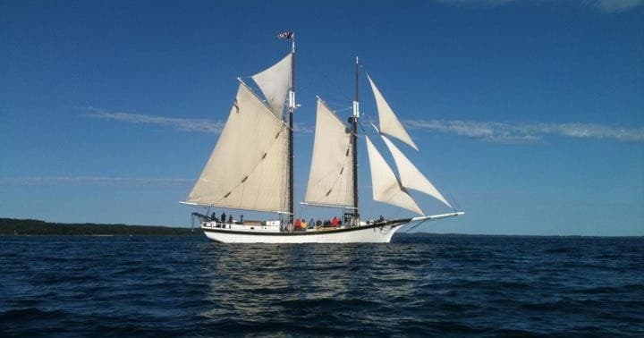 Schooner sailing on open ocean at dusk, coastal cruise