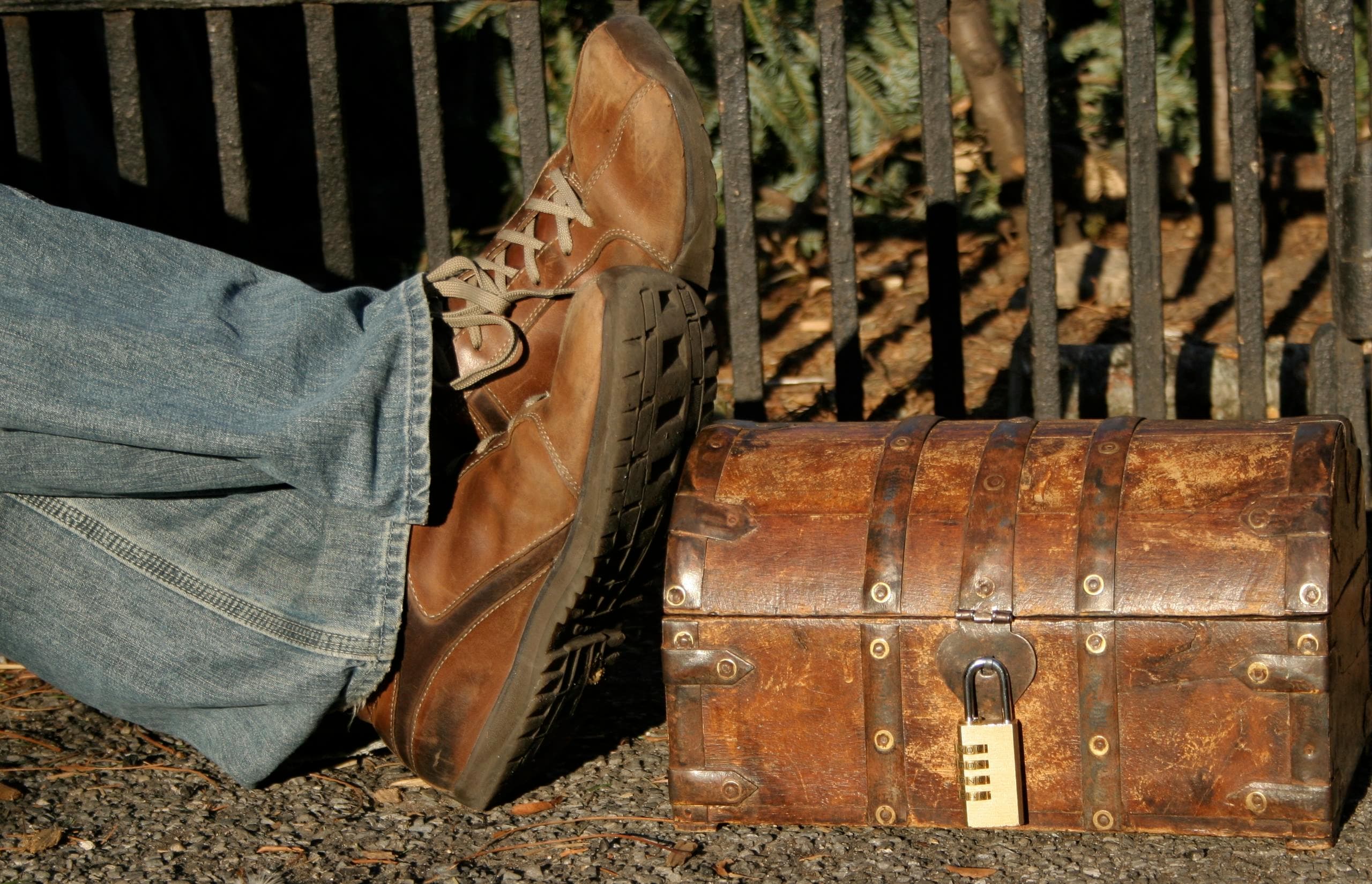 Hiker's boots beside a locked chest on a wooded park trail