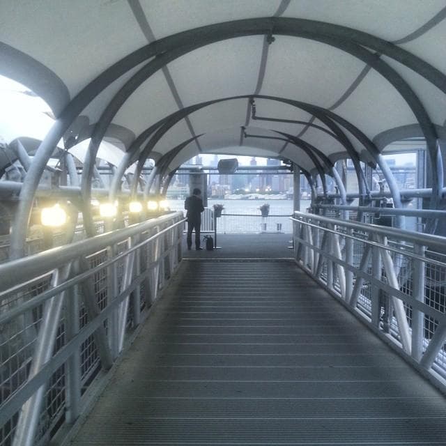 Covered pedestrian pier walkway over river with skyline views