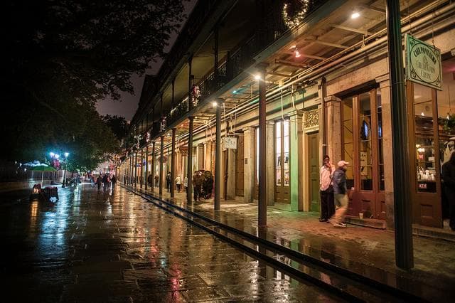 Nighttime French Quarter street with wet reflections