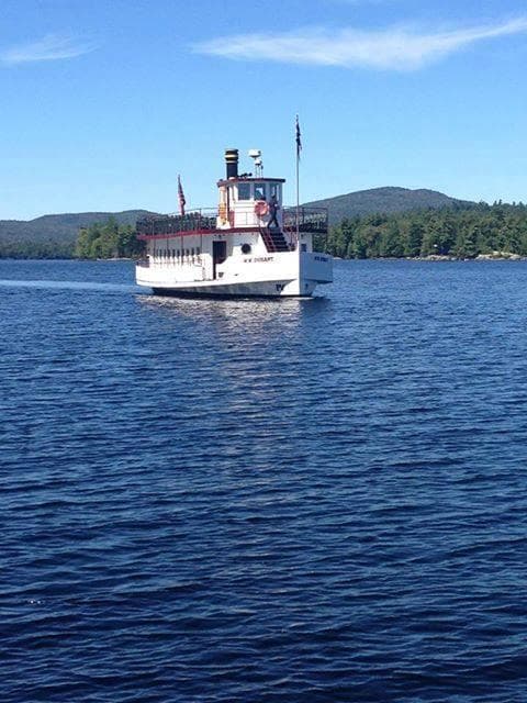 Classic white tour boat on calm Raquette Lake waters