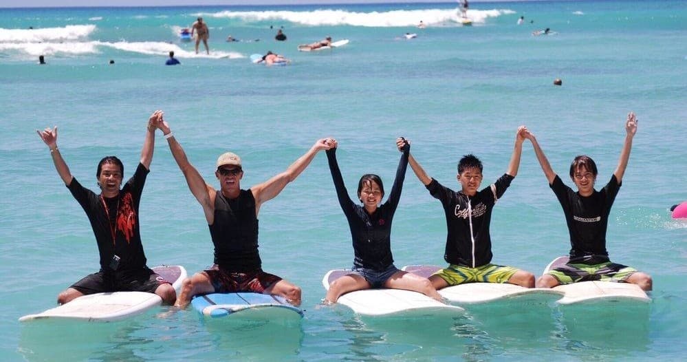 Group surf lesson on longboards in shallow Waikiki surf