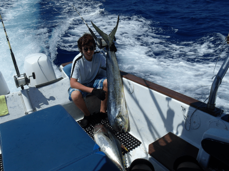 Angler posing with large mahi mahi on a sportfishing boat in Hawaiian waters