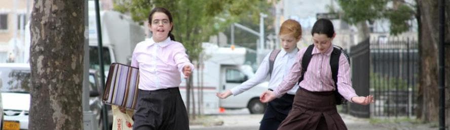 Children walking to school in Hasidic neighborhood on city sidewalk