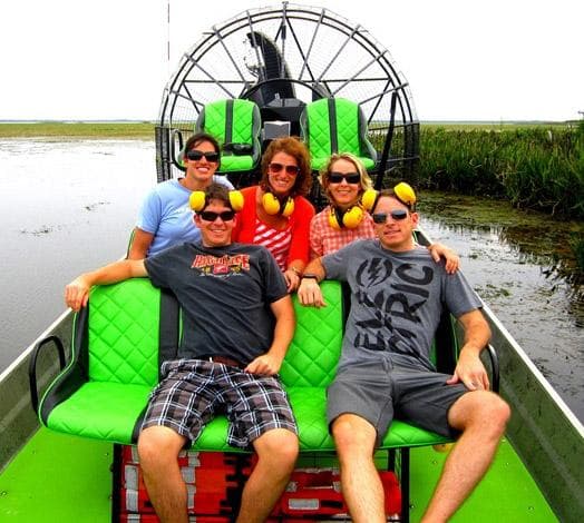 Group seated on vibrant airboat cruising coastal marsh waterways