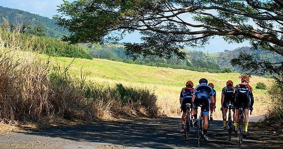 Two cyclists riding along ocean cliff road on Big Island