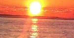 Vibrant sun setting over calm sea at golden hour