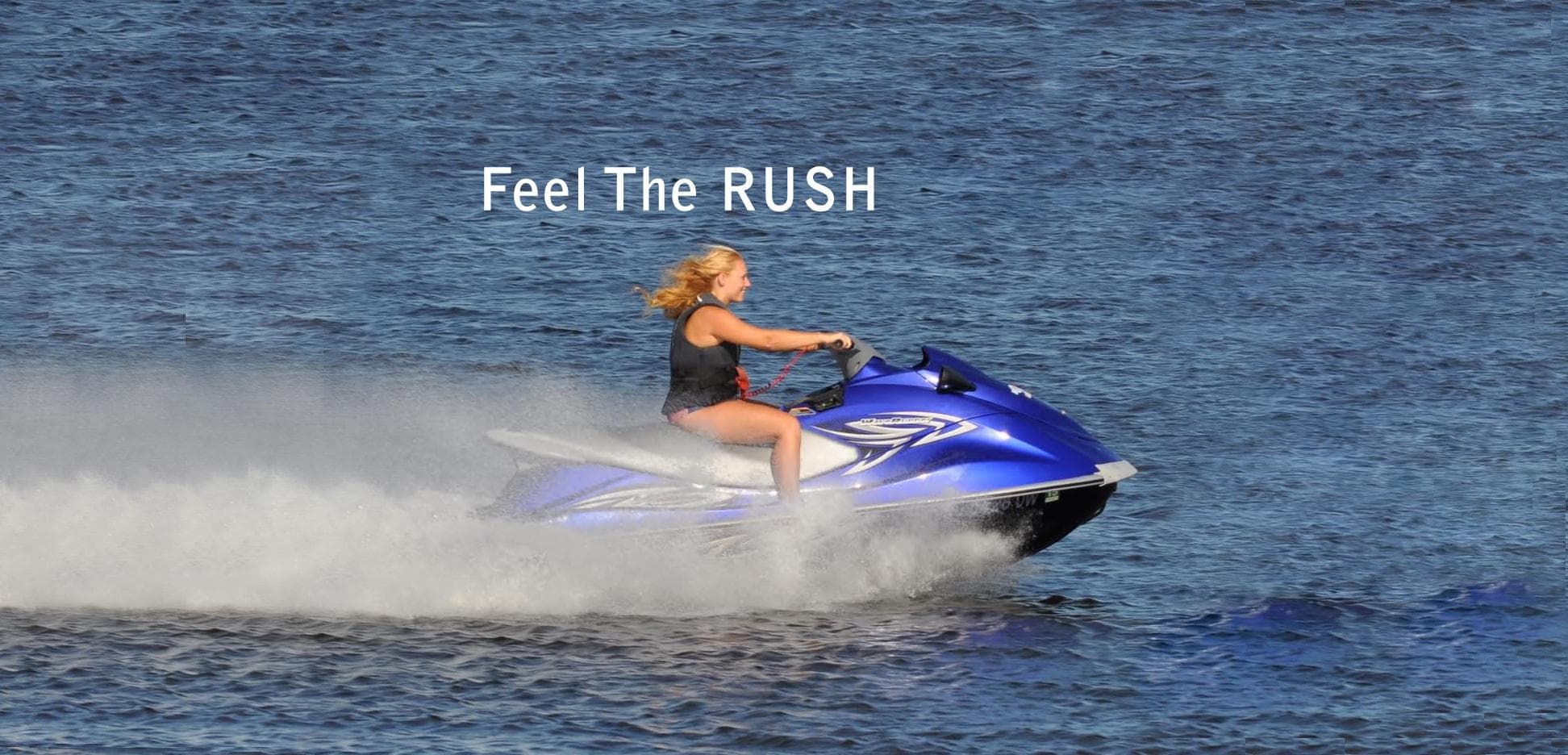 Woman riding jet ski across open ocean with water spray