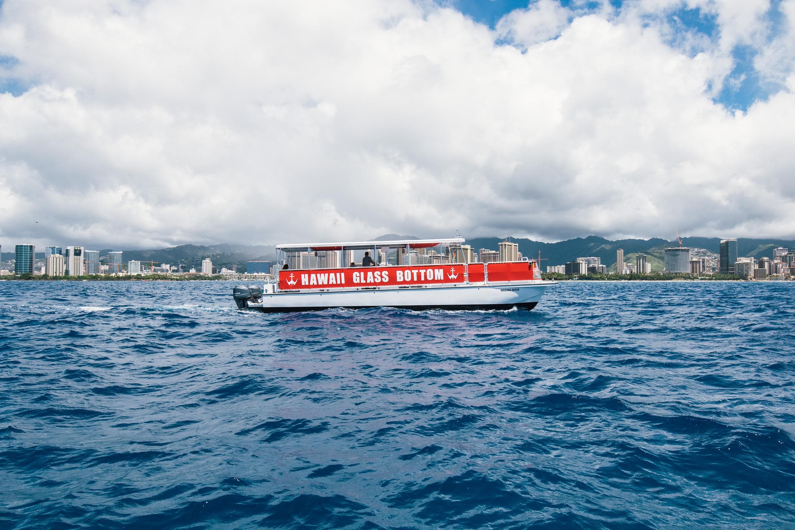 Red-top glass-bottom boat cruising blue Pacific waters off Oahu