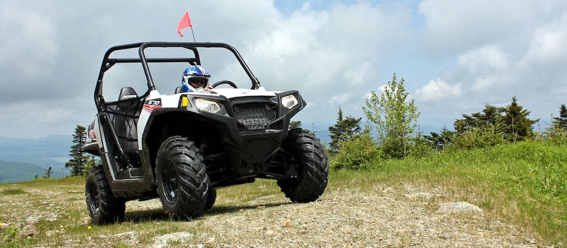 Single off-road ATV on rocky trail under expansive sky in mountains