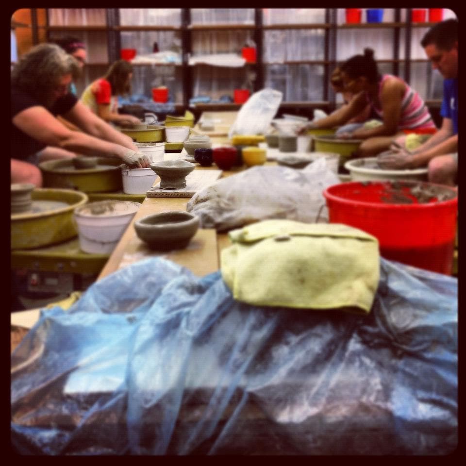 Students shaping clay on pottery wheels in studio class