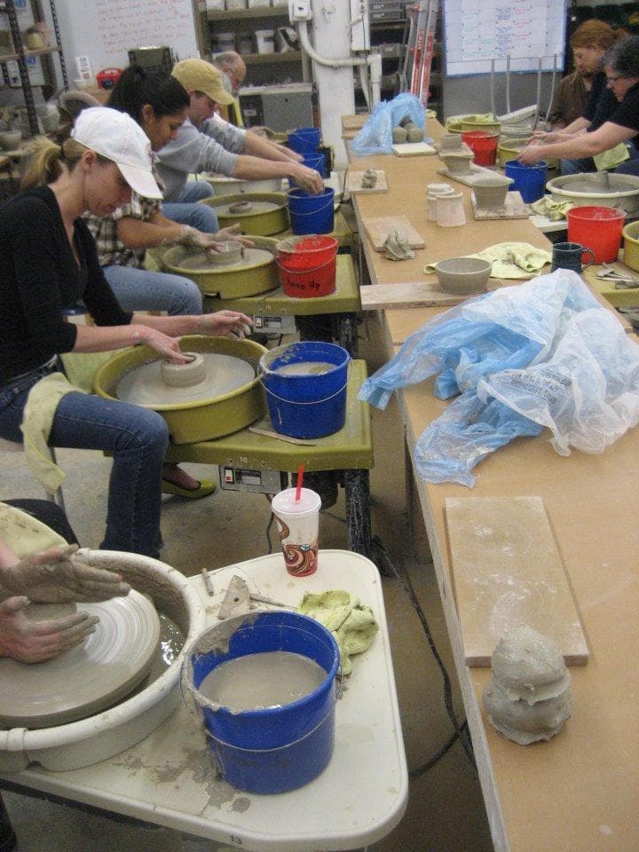 Pottery students practicing wheel throwing in busy studio