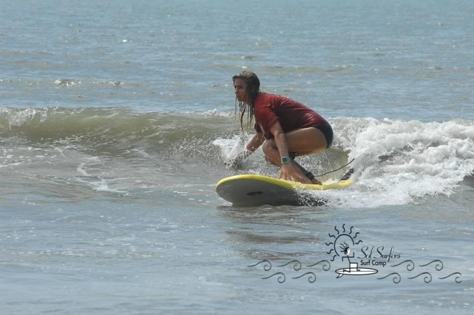 Female surfer crouching on yellow board in ocean wave