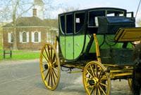 Antique green carriage parked near colonial buildings in Williamsburg tour