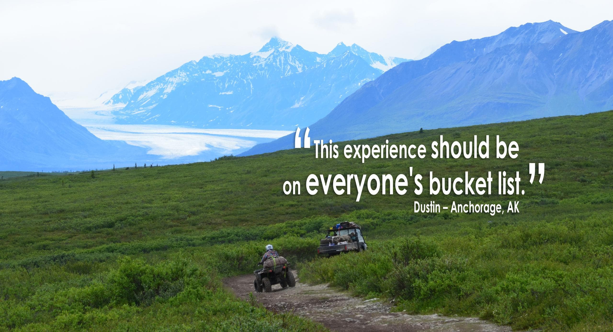 Off-road trail across green tundra with broad mountain vistas