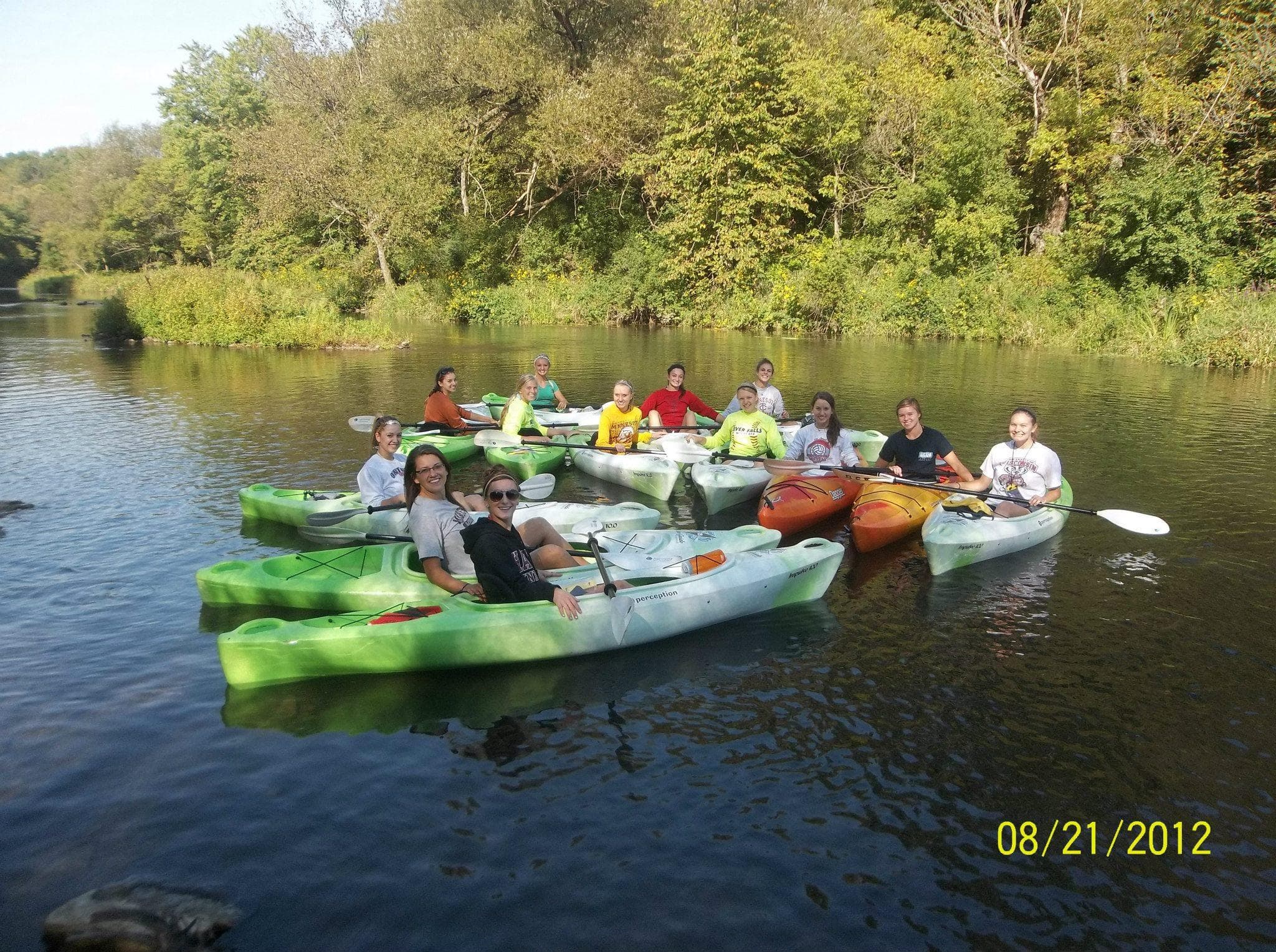 Group of kayakers floating together on tranquil forest river