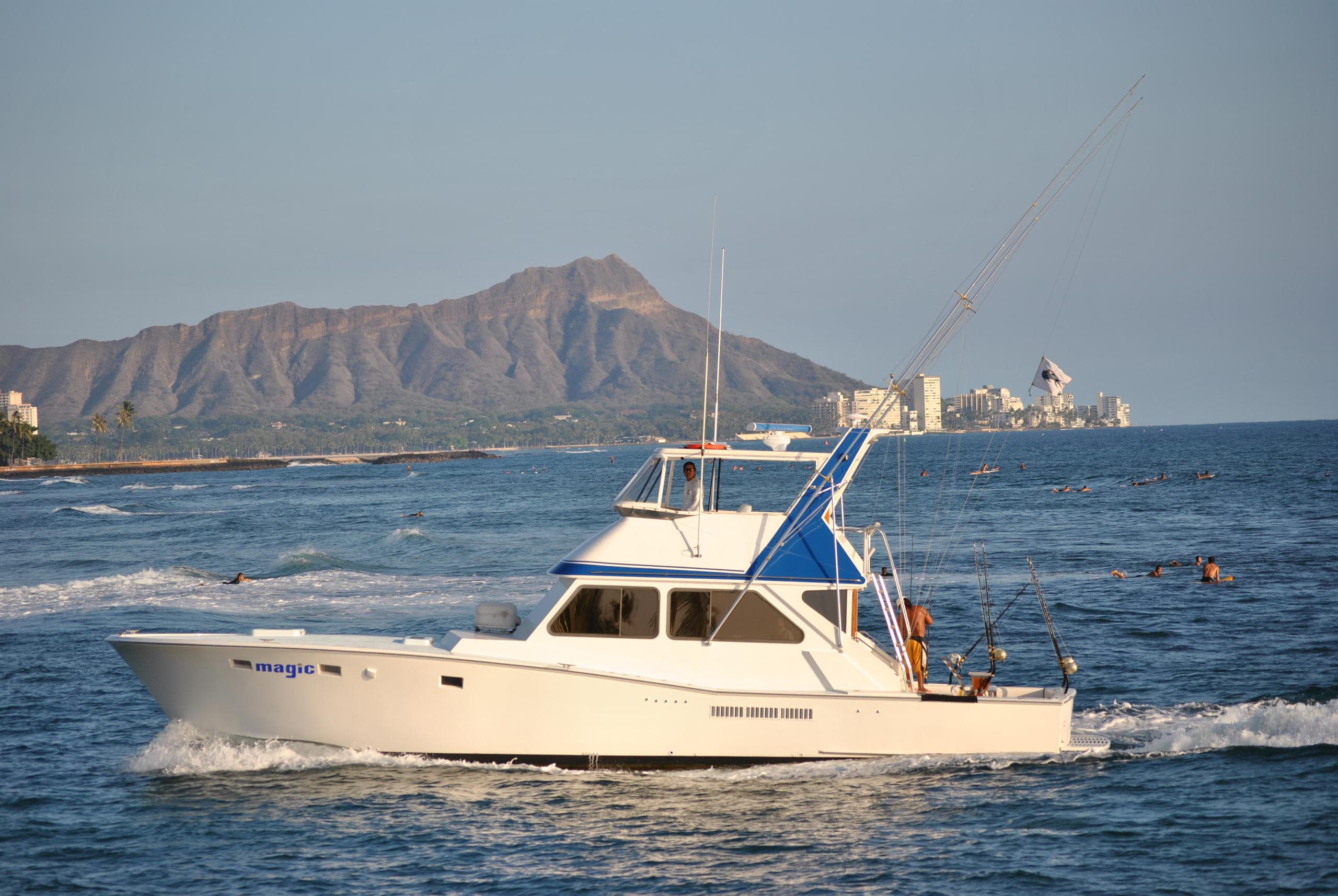 Fishing reels and outriggers on charter boat wake, offshore waters