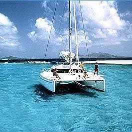 Catamaran sailing on clear tropical ocean under blue sky