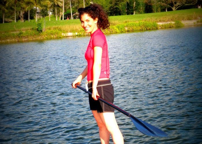 Woman paddleboarding on calm lagoon waters near shore