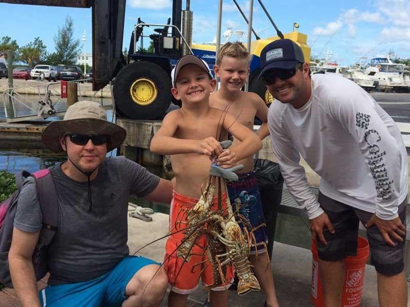 Group holding fresh lobsters at marina after deep-sea fishing