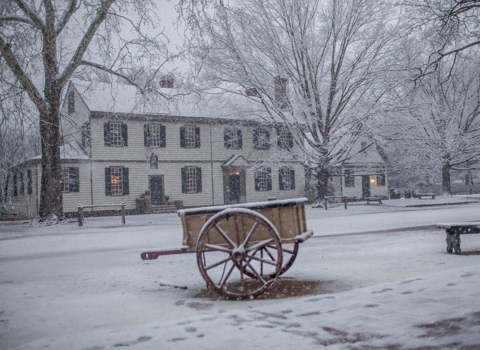 Snow-covered colonial street with wooden wagon in Williamsburg scene