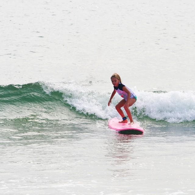 Surfer riding pink surfboard on breaking ocean wave