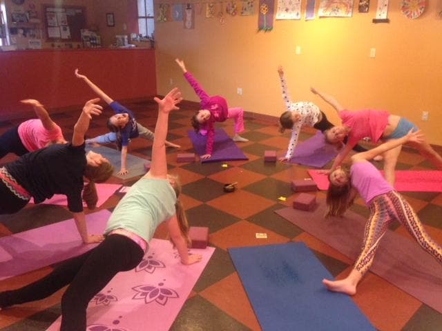 Kids in indoor yoga class stretching on mats in studio session