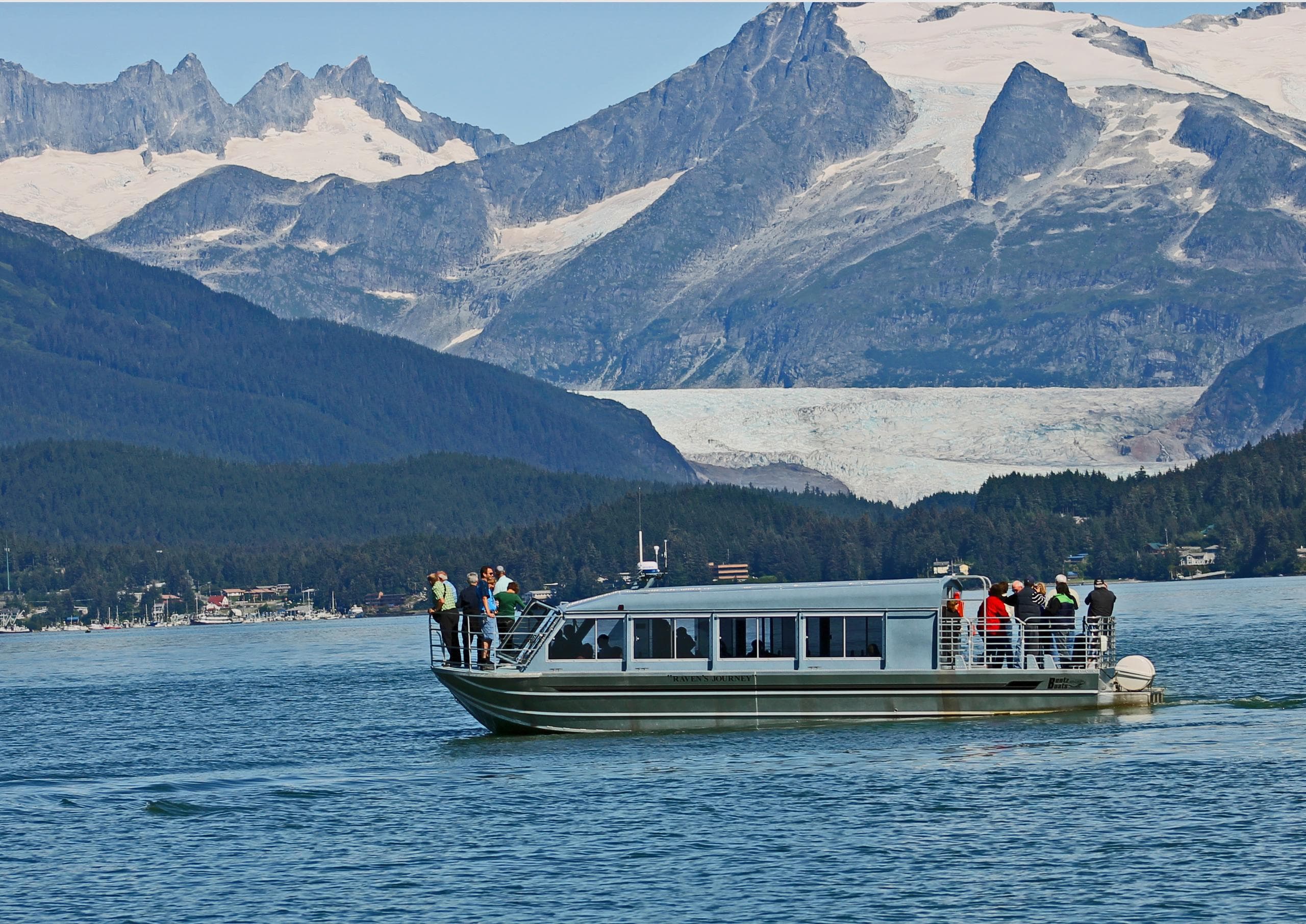 Tour boat cruising coastal waters with snowcapped mountains