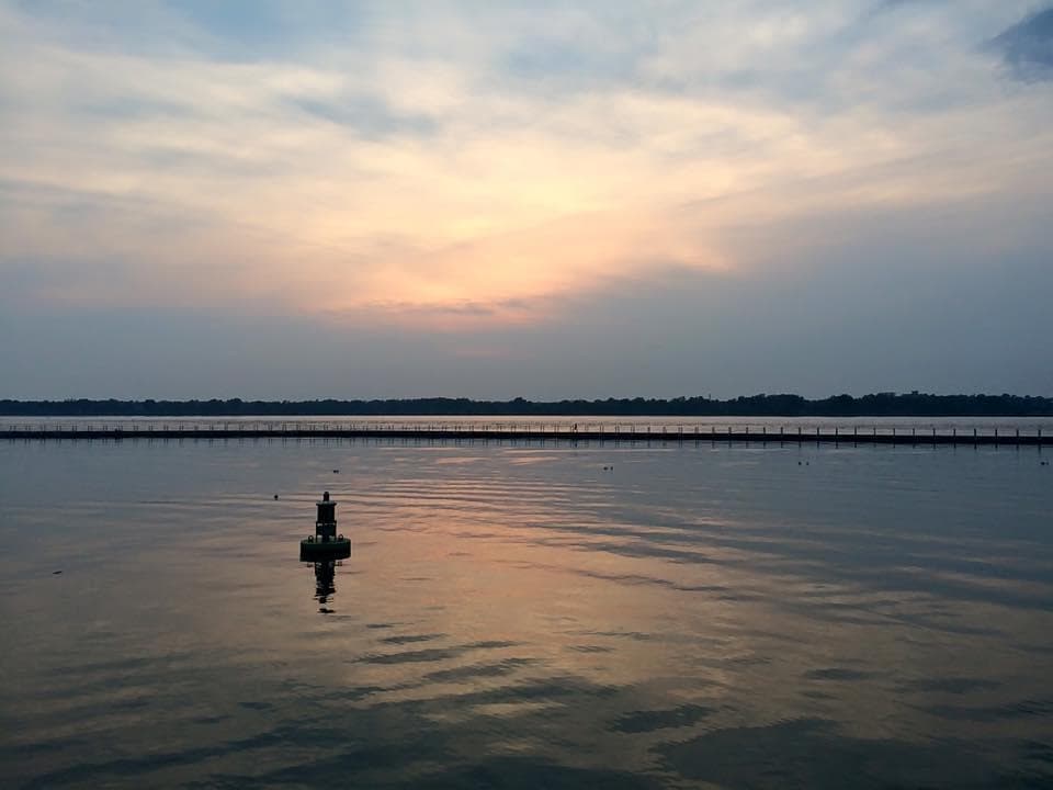 Calm lake sunset with buoy marking channel during evening cruise
