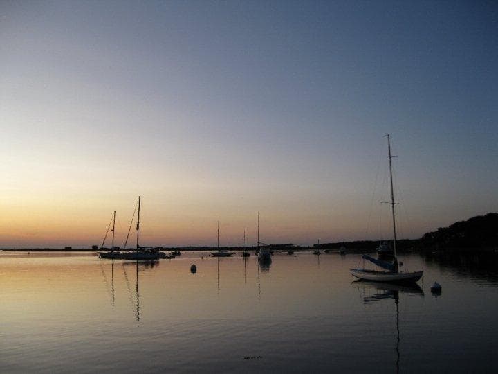 Sailboats moored at sunset in calm harbor, tranquil sea view