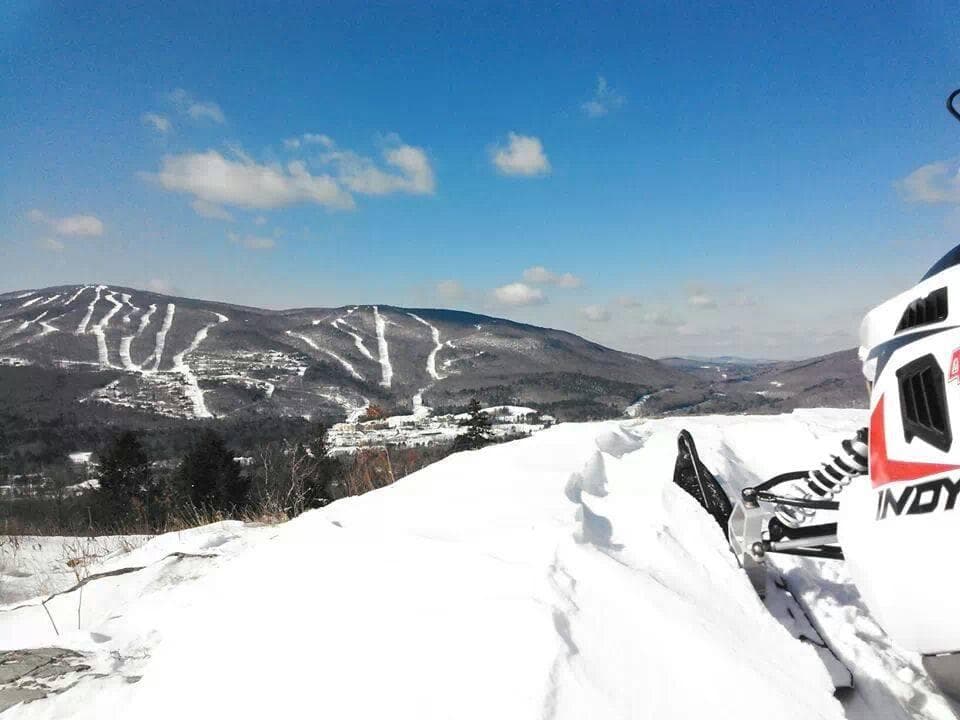 Snowmobiles overlooking snowy mountain vista and ski trails