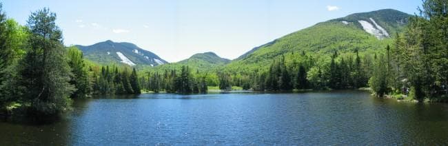 Calm reflective lake framed by green hills and blue sky
