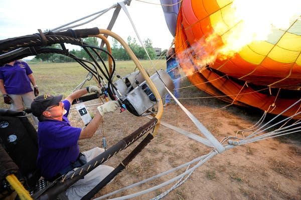 Ground crew igniting burner while preparing hot air balloon