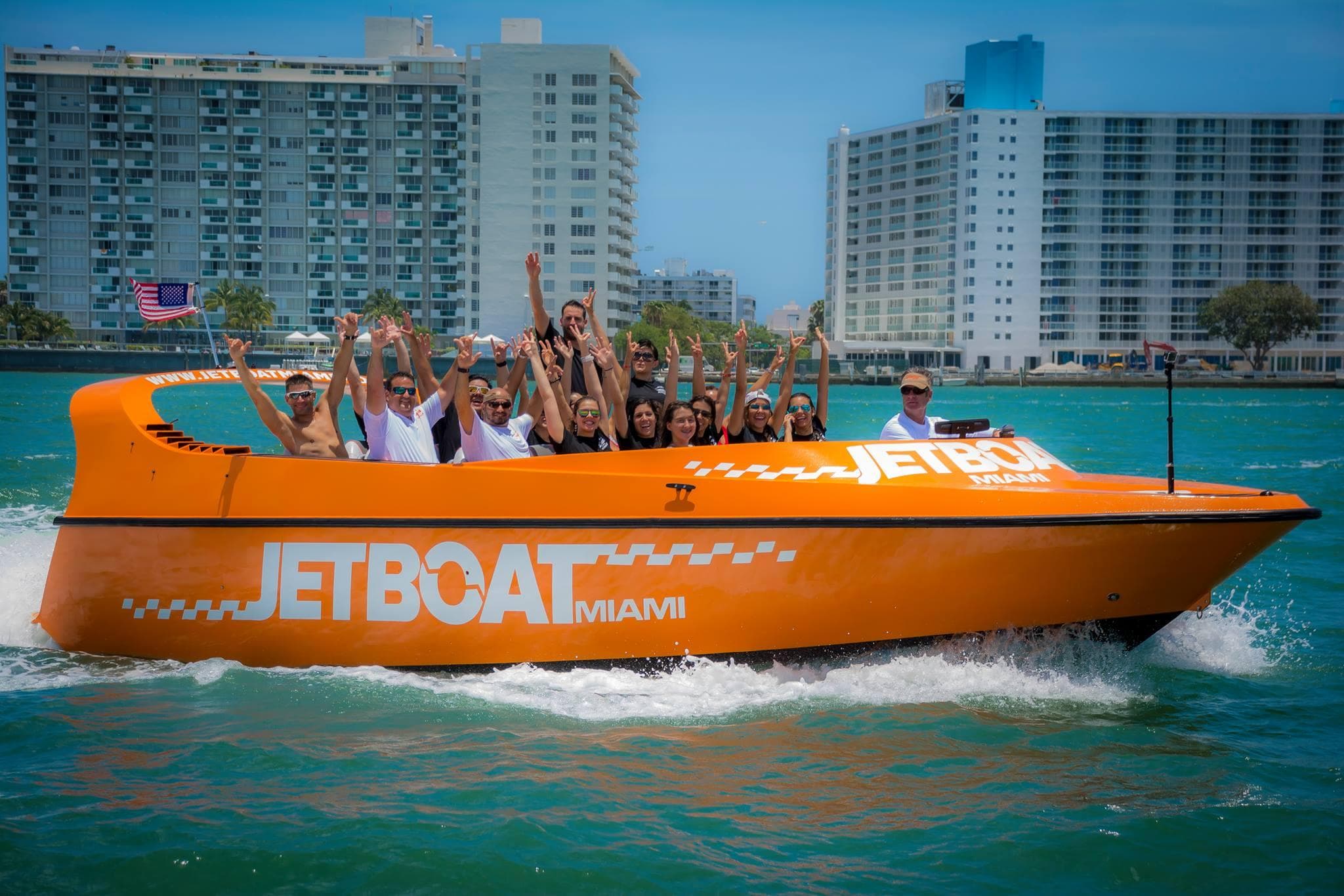 Orange jet boat with cheering riders cruising Miami bay