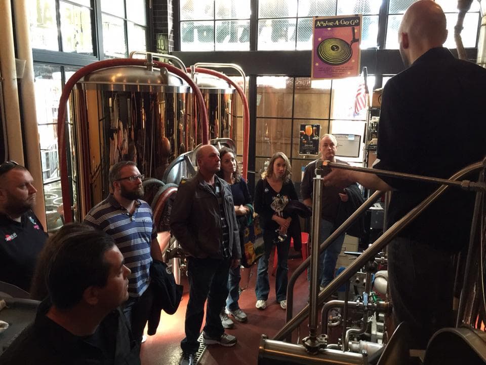 Guided brewery tour among copper fermenters inside taproom