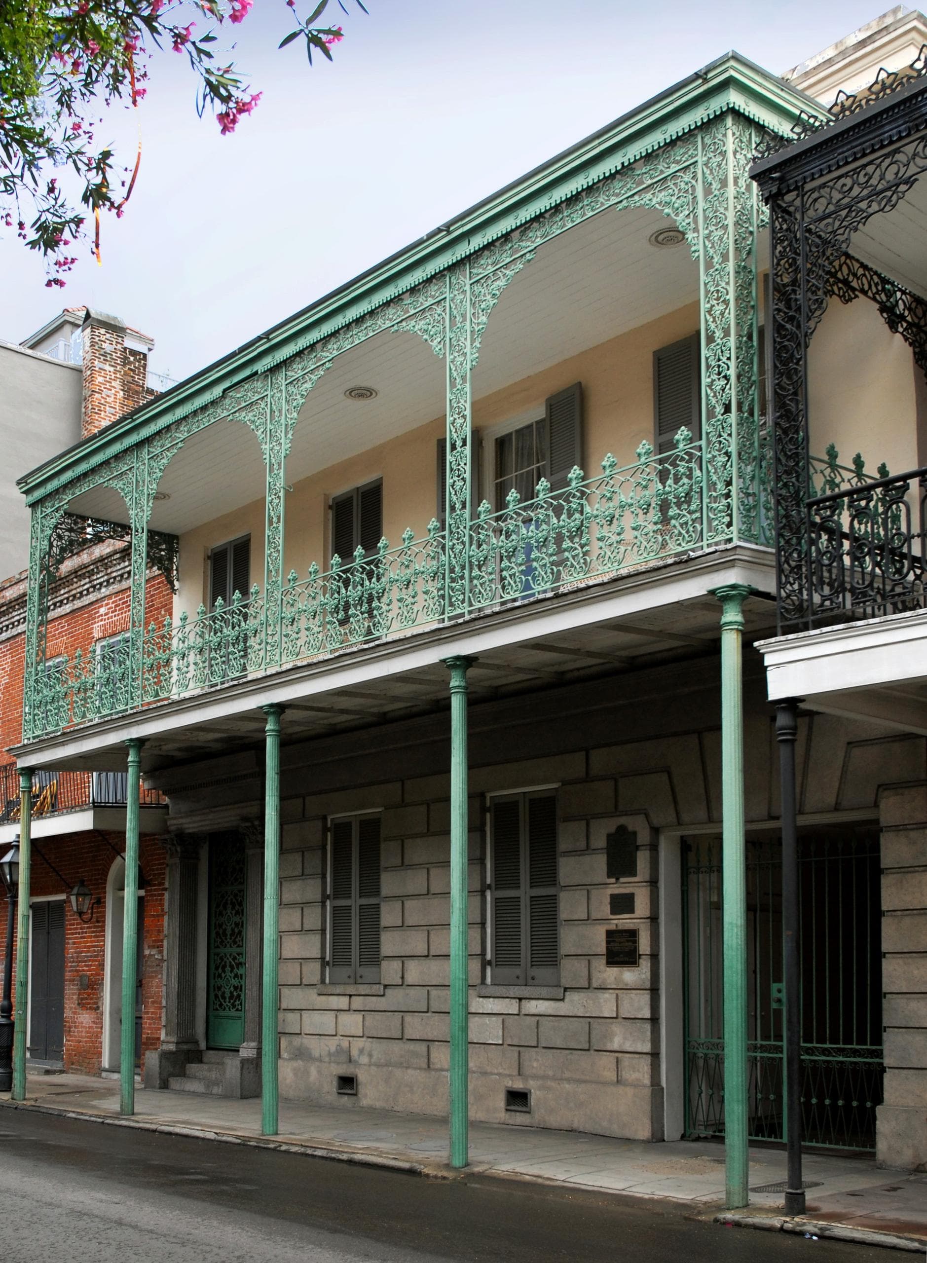 Two-story cast-iron balcony facade on narrow urban street, exterior