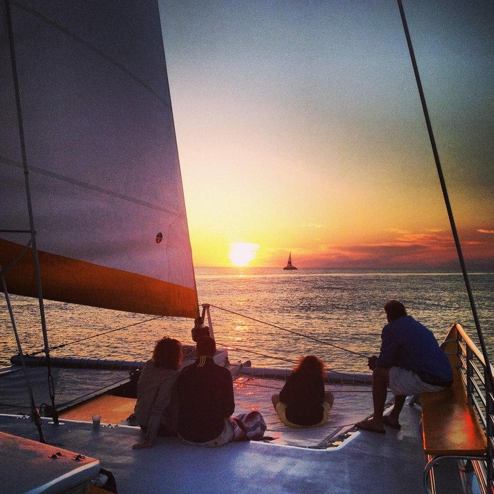 Passengers watching sunset from catamaran deck on ocean cruise