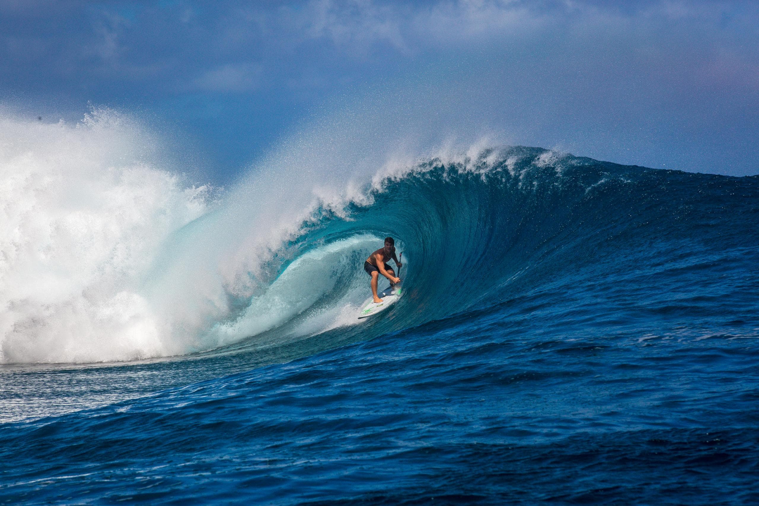 Surfer riding a perfect barreling wave off Maui reef break
