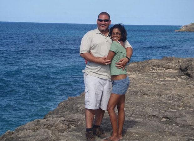 Couple embracing on coastal cliff with ocean vista at shore