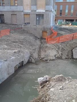 Urban excavation site with exposed foundations and muddy pools