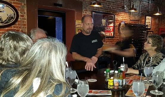Food tour group enjoying chef demonstration inside lively local restaurant