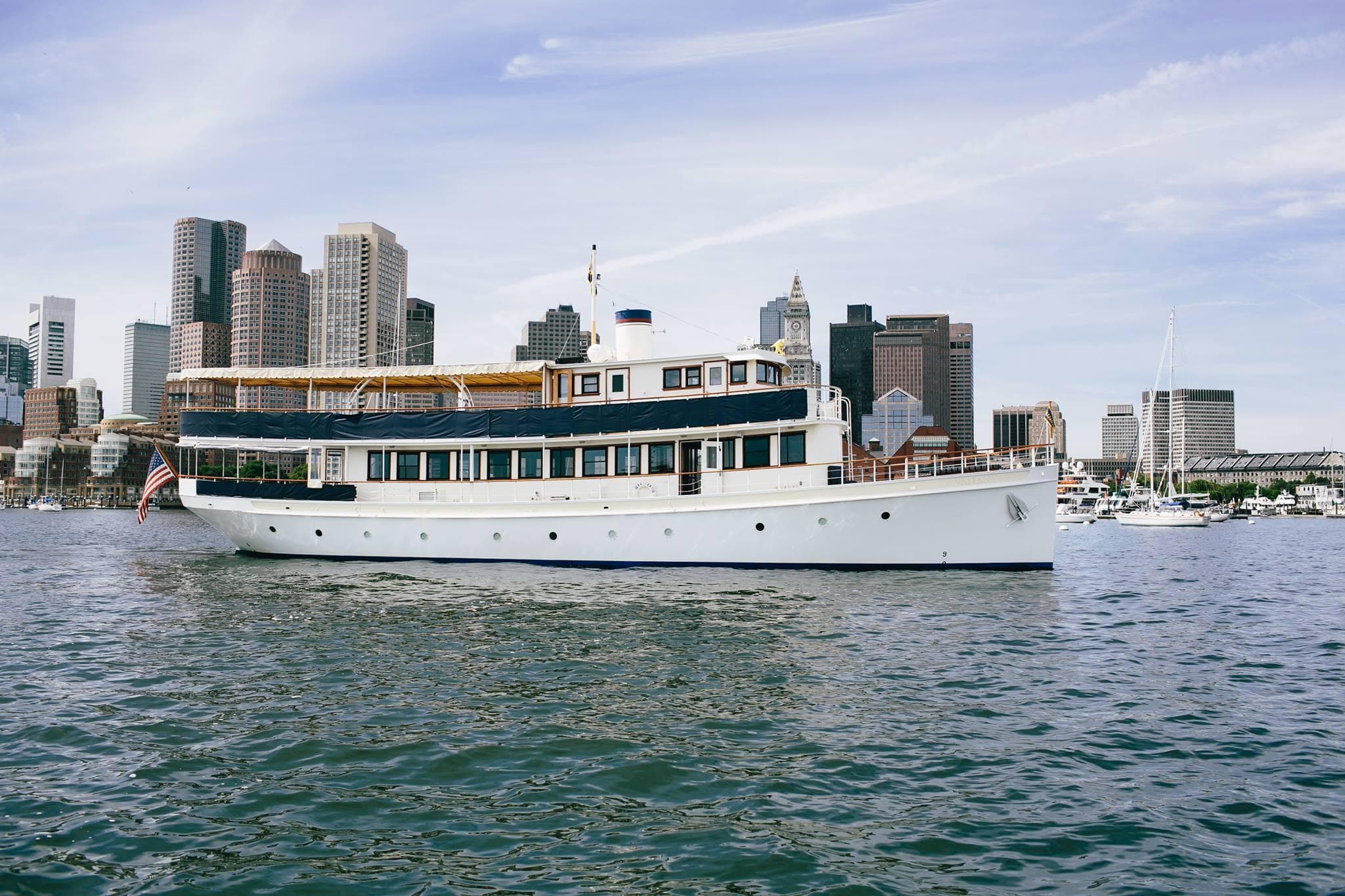 White passenger yacht cruising Boston harbor with skyline