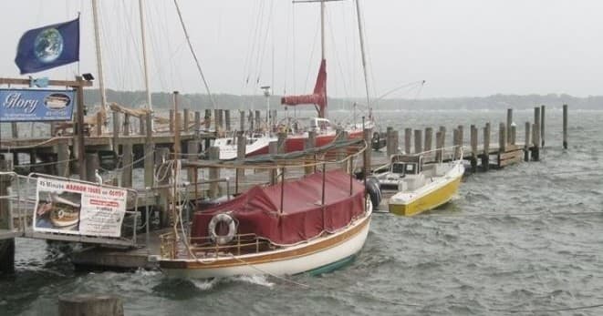 Sailboat moored at marina with overcast coastal harbor backdrop
