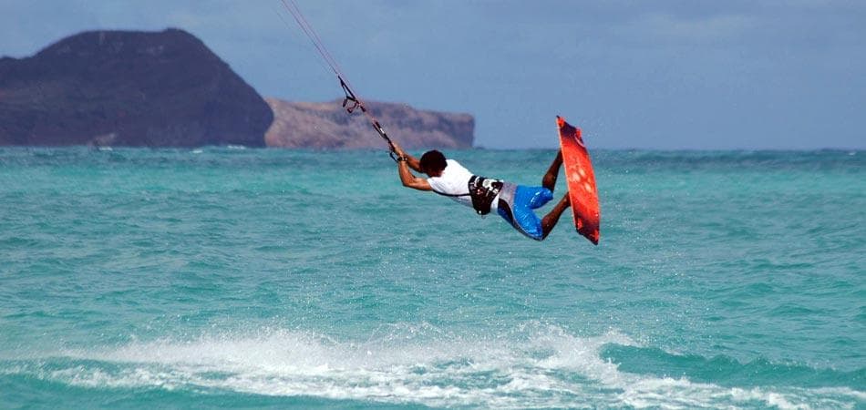 Kiteboarder jumping over turquoise ocean off Hawaii coast