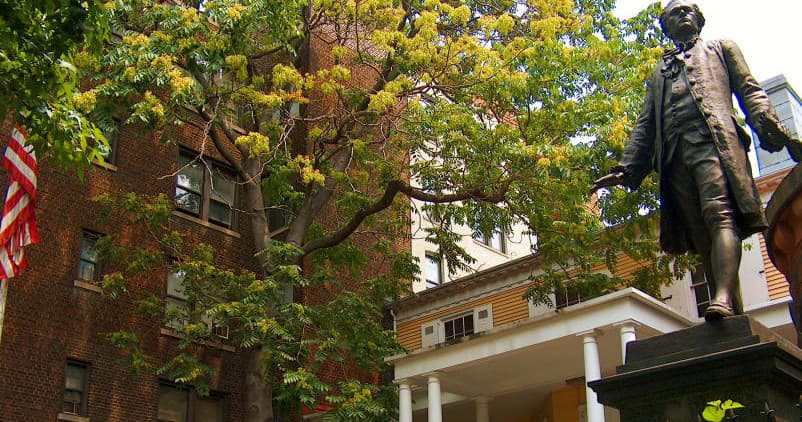 Outdoor bronze statue in historic urban park with leafy trees